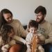 A joyful family of four sitting together on a sofa, enjoying their time with toys.